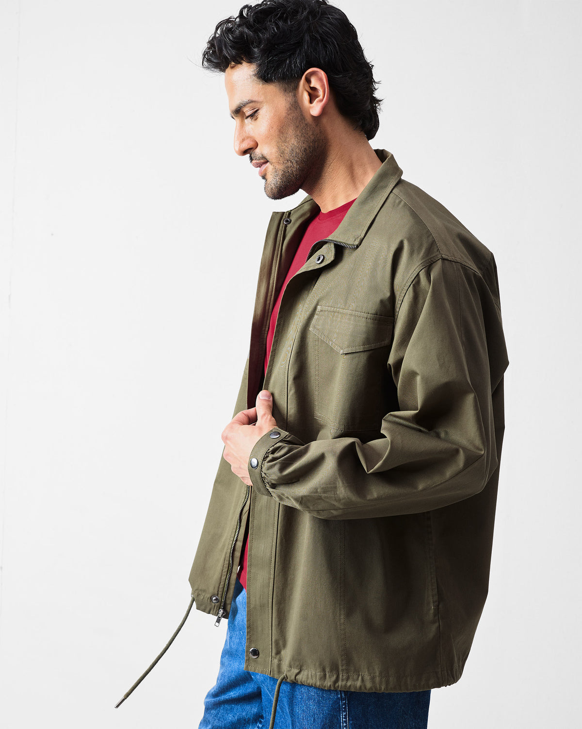 Side view of an olive utility jacket with elastic cuff and drawstring hem.