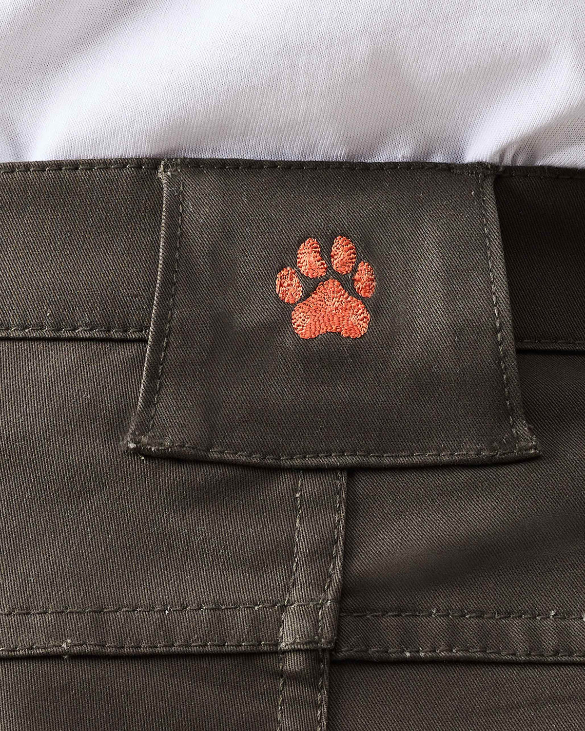 Close-up of deep olive Boscage pants showing an orange paw on the belt loop.