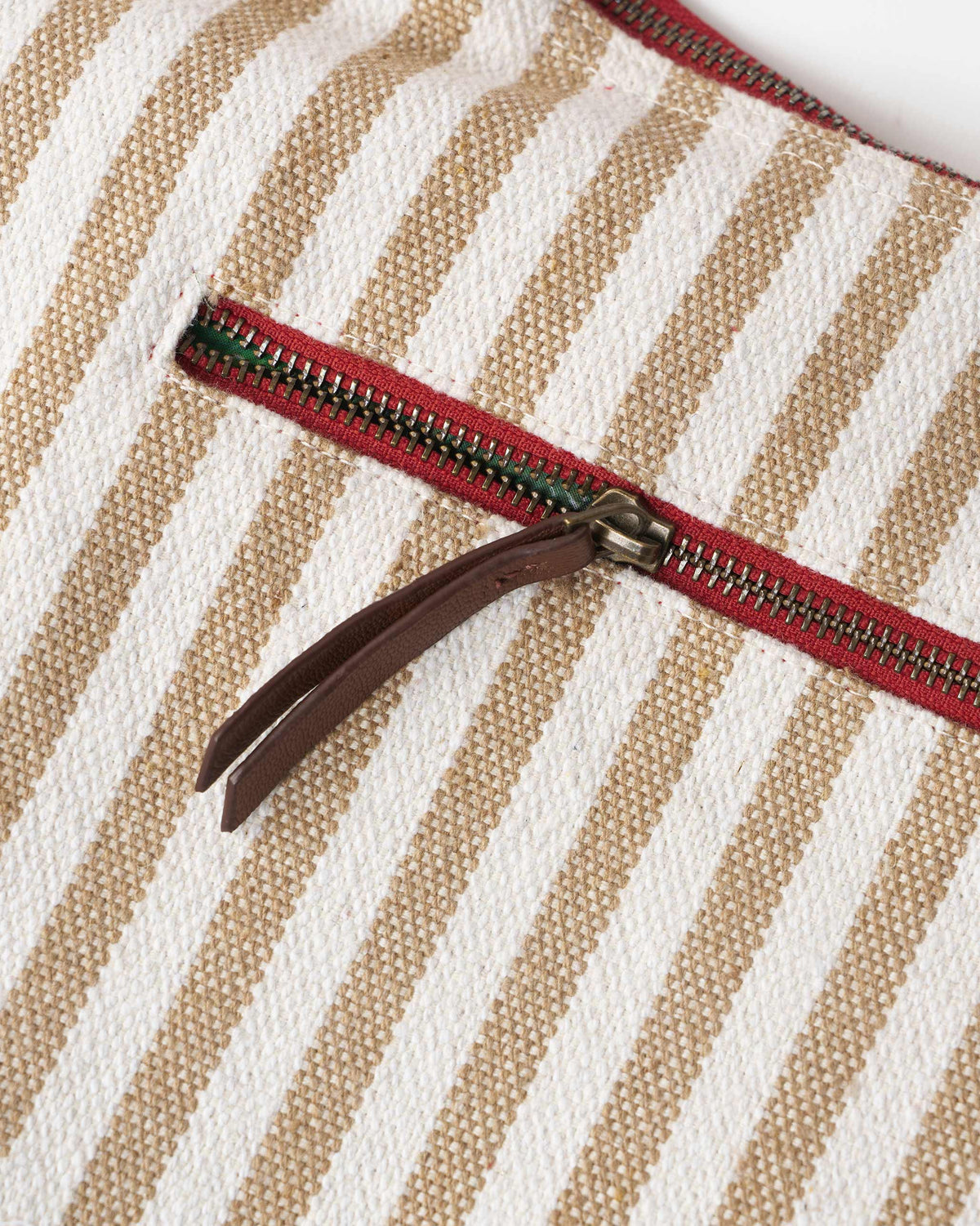 Close-up of a Wayfarer bag showing a red zipper with a leather pull.