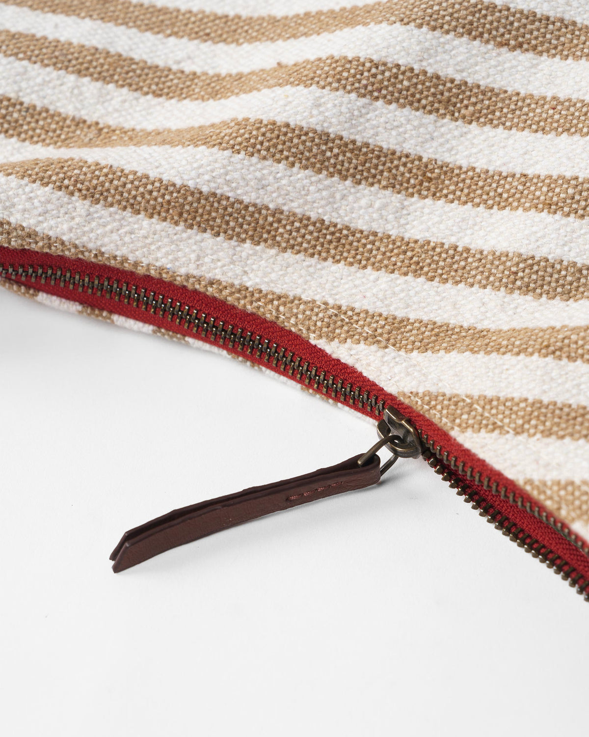 Close-up of a Wayfarer bag showing a red zipper on striped canvas.