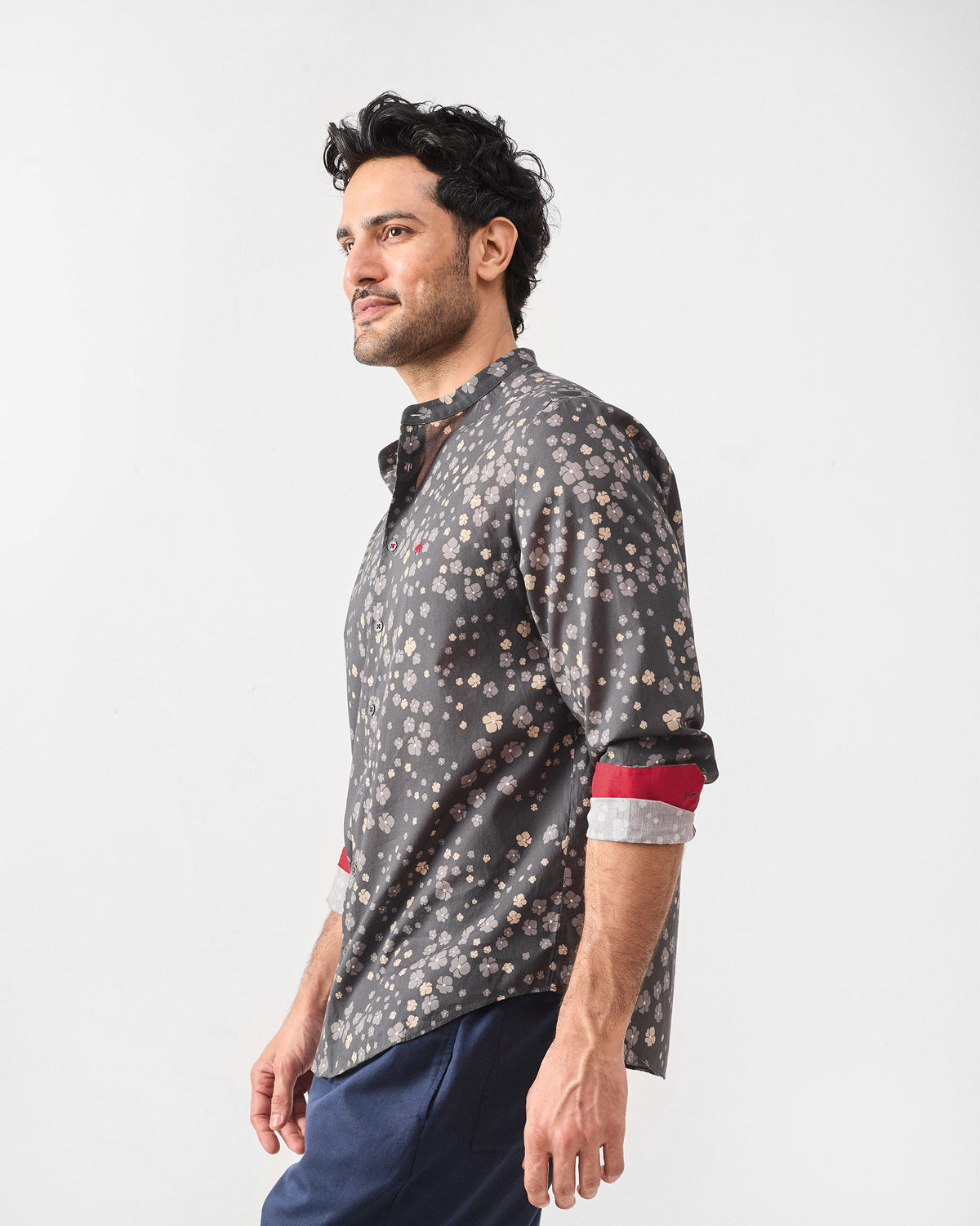 Side view of a charcoal Nawab Shirt with a floral print and red contrast cuffs.