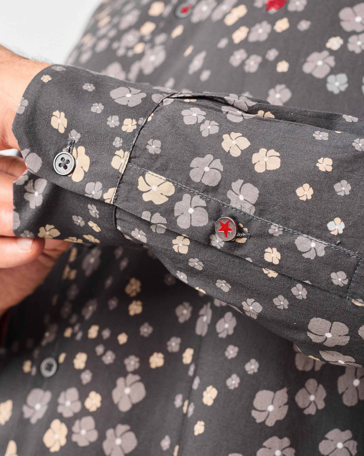Close-up of a charcoal Nawab Shirt cuff showing floral print and a red star button.