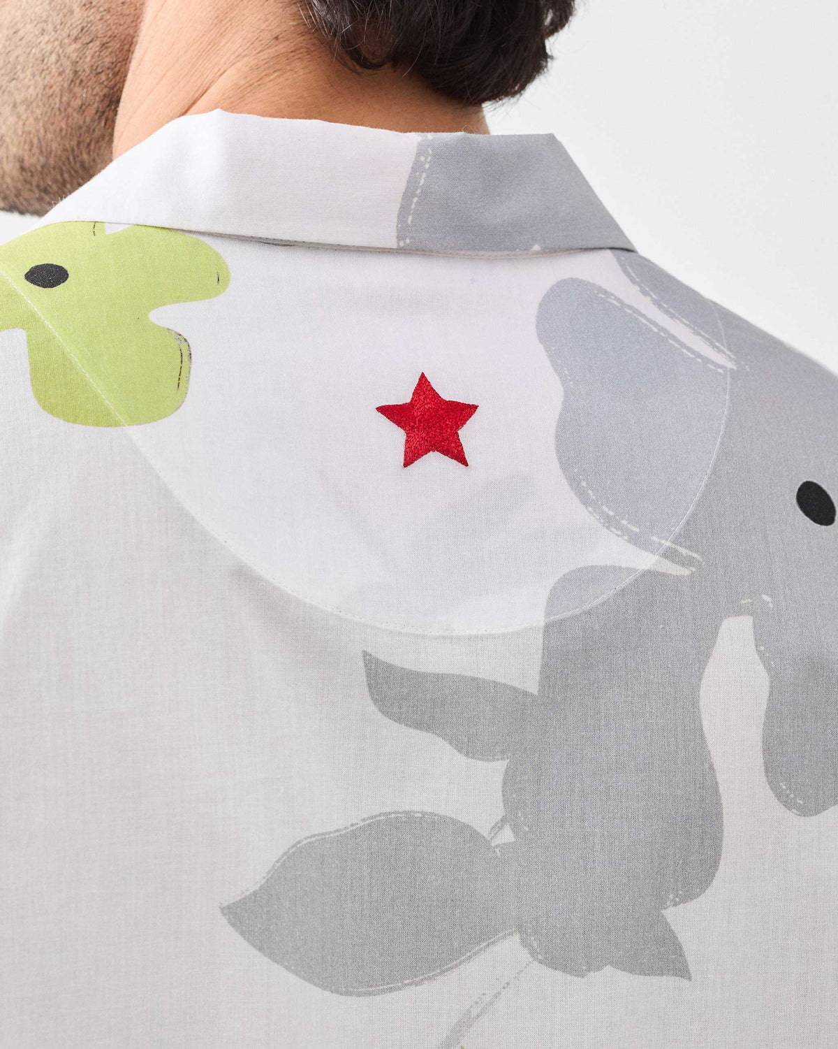 Close-up of the red embroidered star on the back of a white Mistari Shirt.