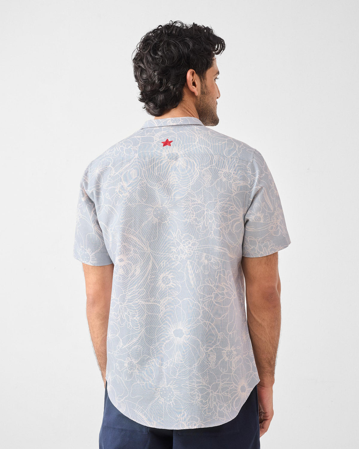Back of a grey Riverline shirt with floral print and a red embroidered star.