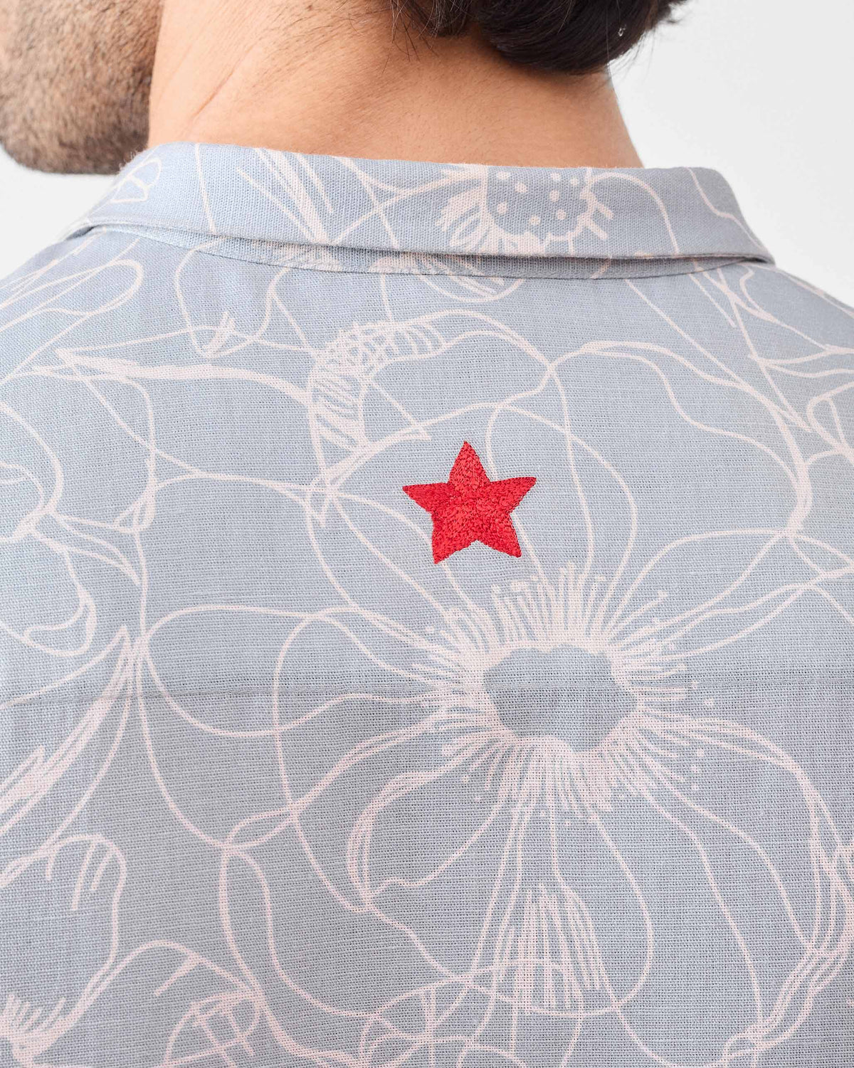 Close-up of a red star on the back of a grey floral Riverline shirt.