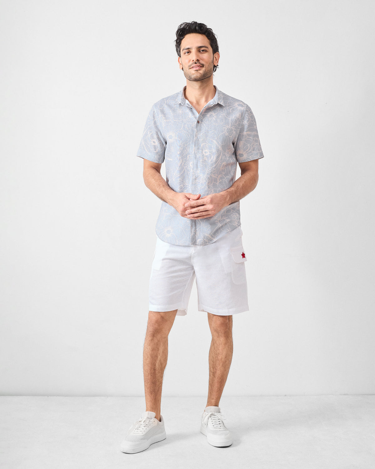 Person wearing a grey floral Riverline shirt with white shorts.