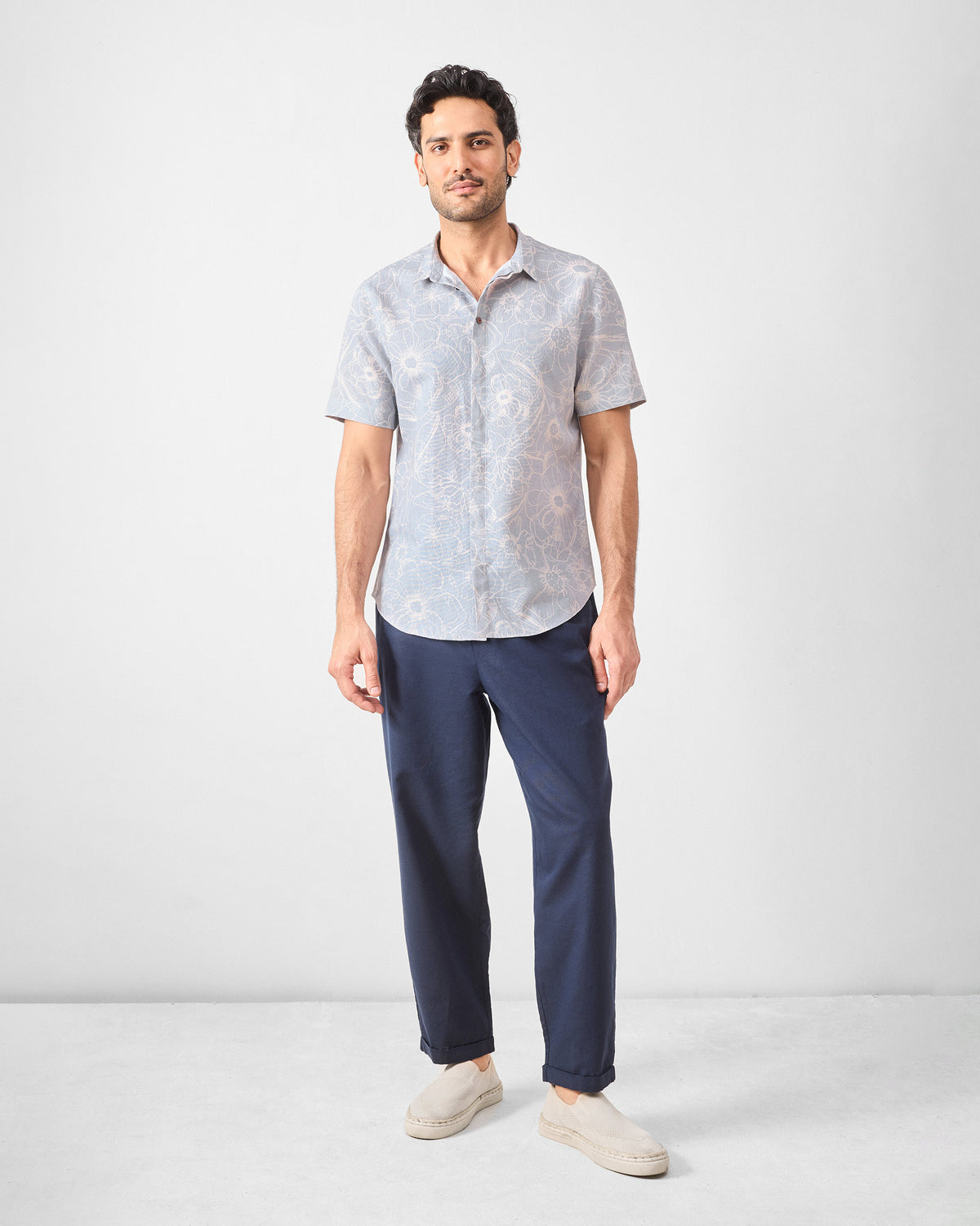 Person wearing a grey floral Riverline shirt with navy trousers.