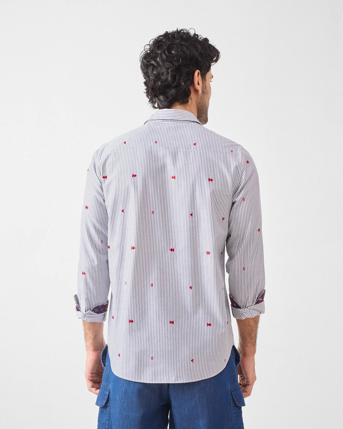 Back of a white pinstripe Hakuna Shirt with scattered red embroidery.