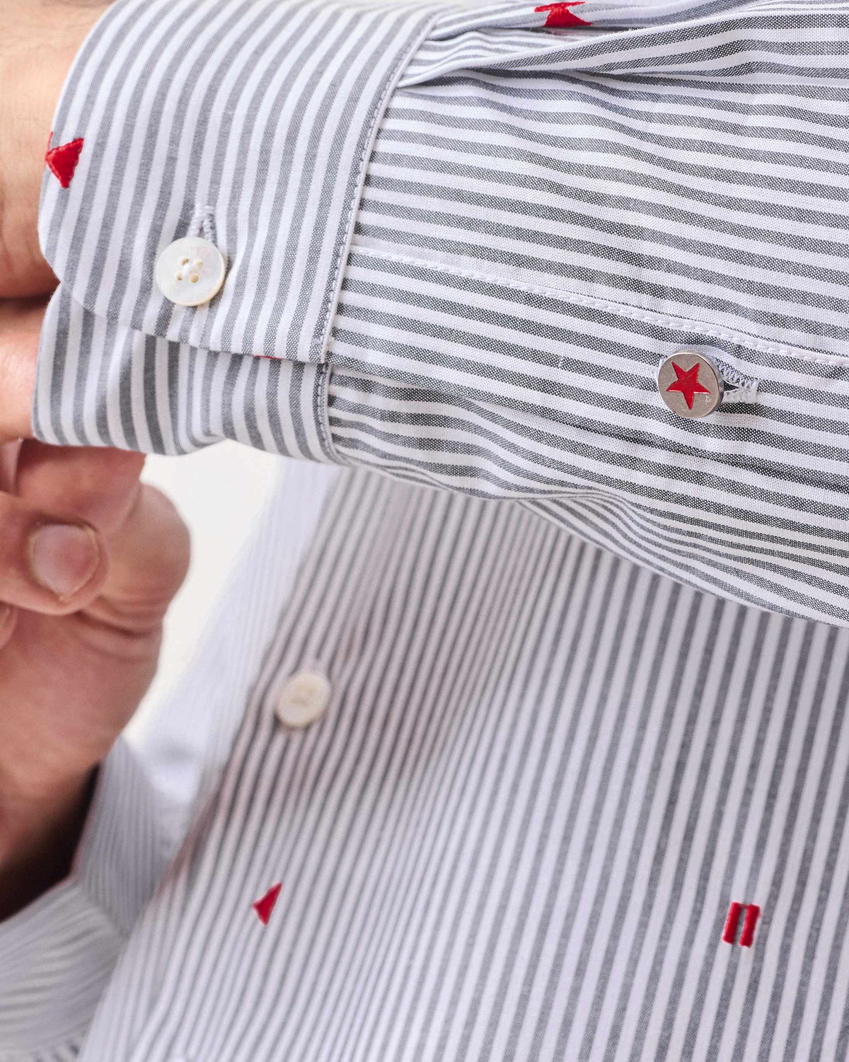 Close-up of a Hakuna Shirt cuff with red star embroidery and a star button.