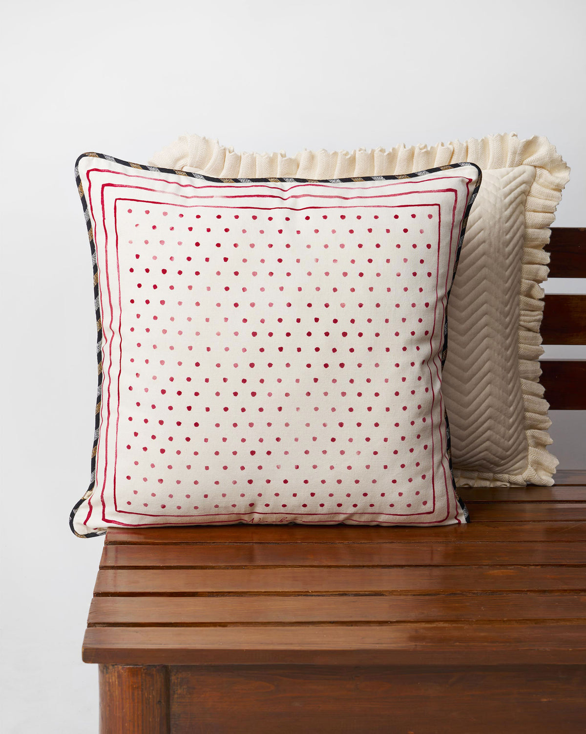 Cream cushion cover with red dots and a red border line.