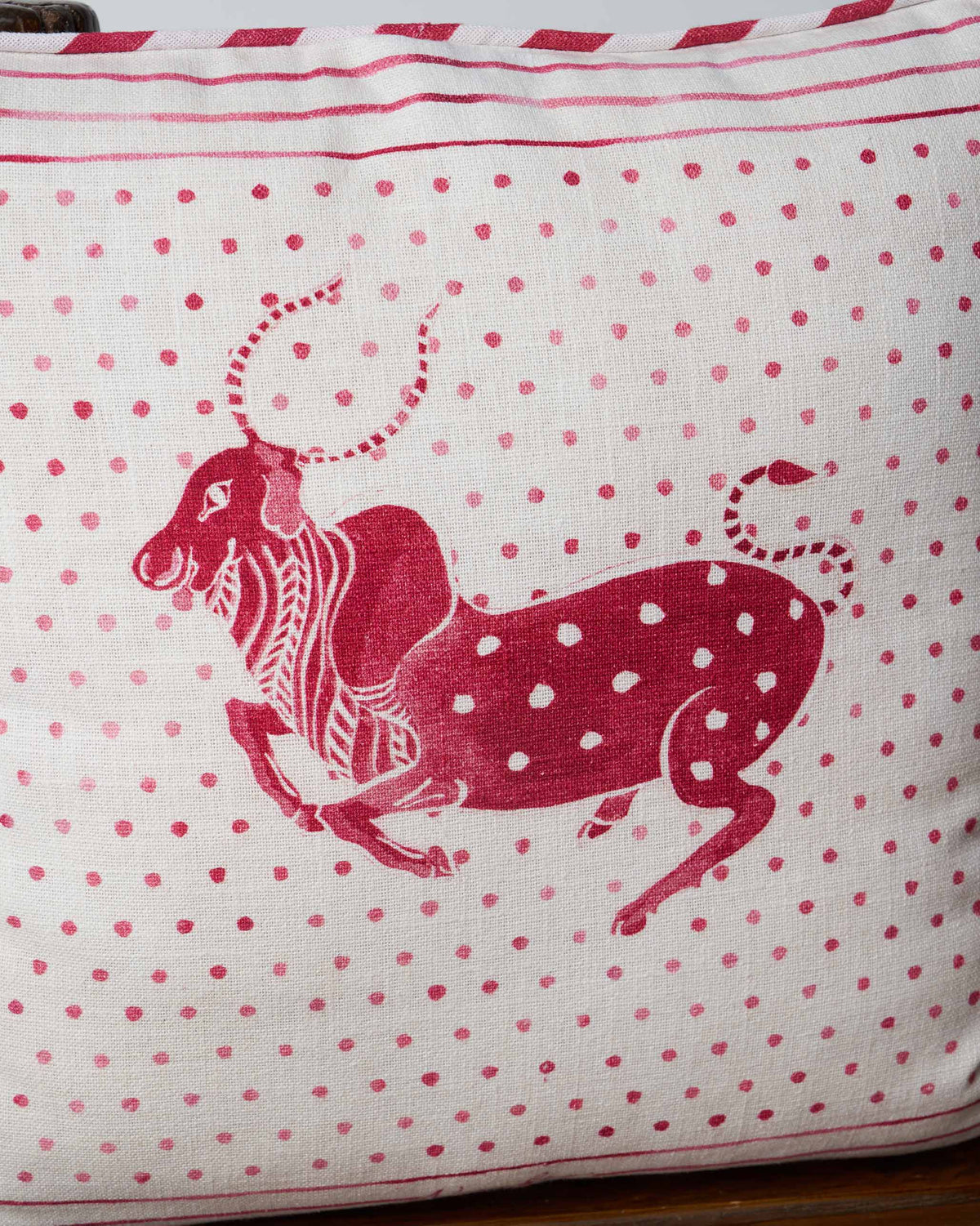 Close-up of the Leaping Bull cushion cover showing the red bull motif and dot pattern.