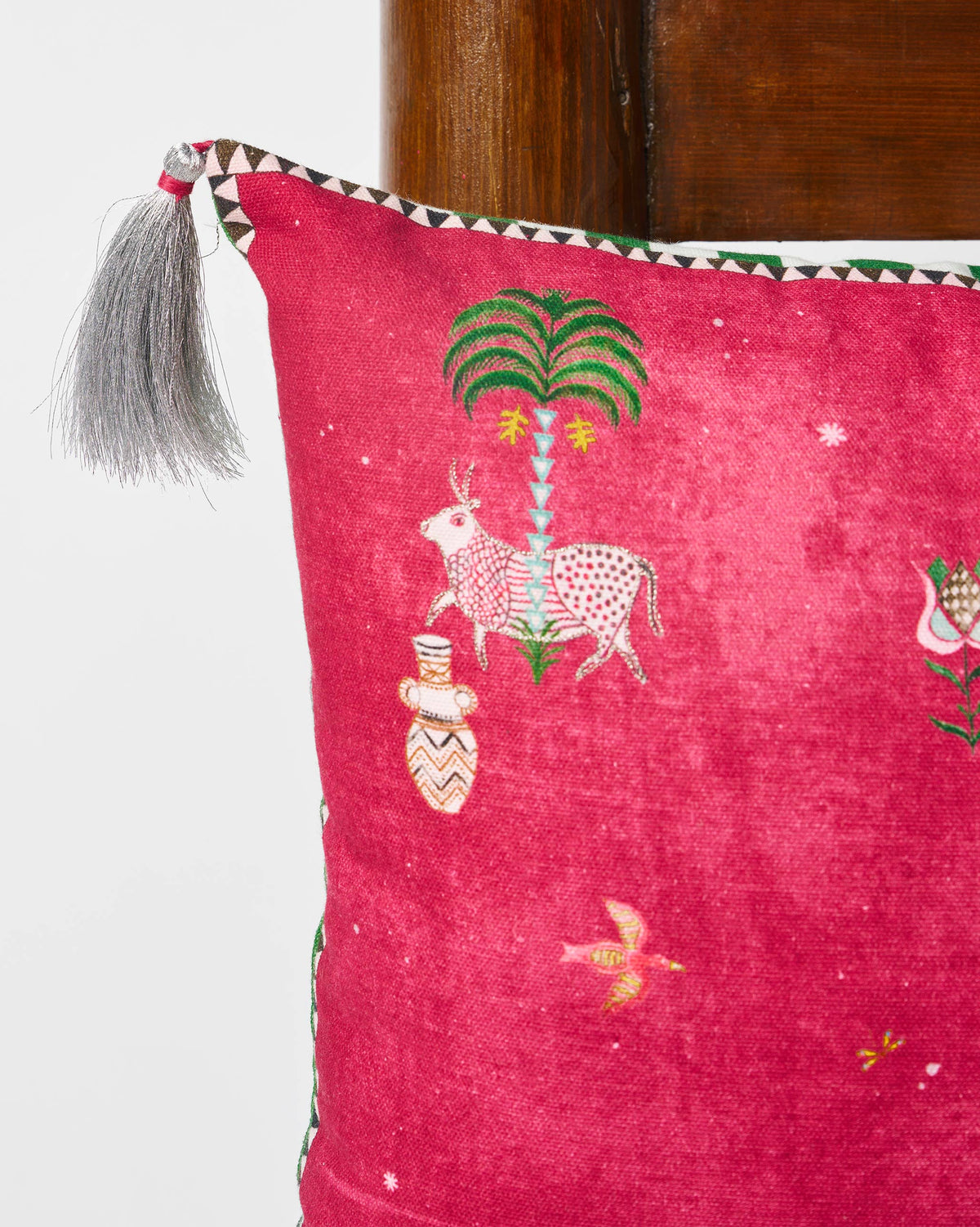 Close-up of a Harappa cushion cover showing a spotted cow beside a palm tree.