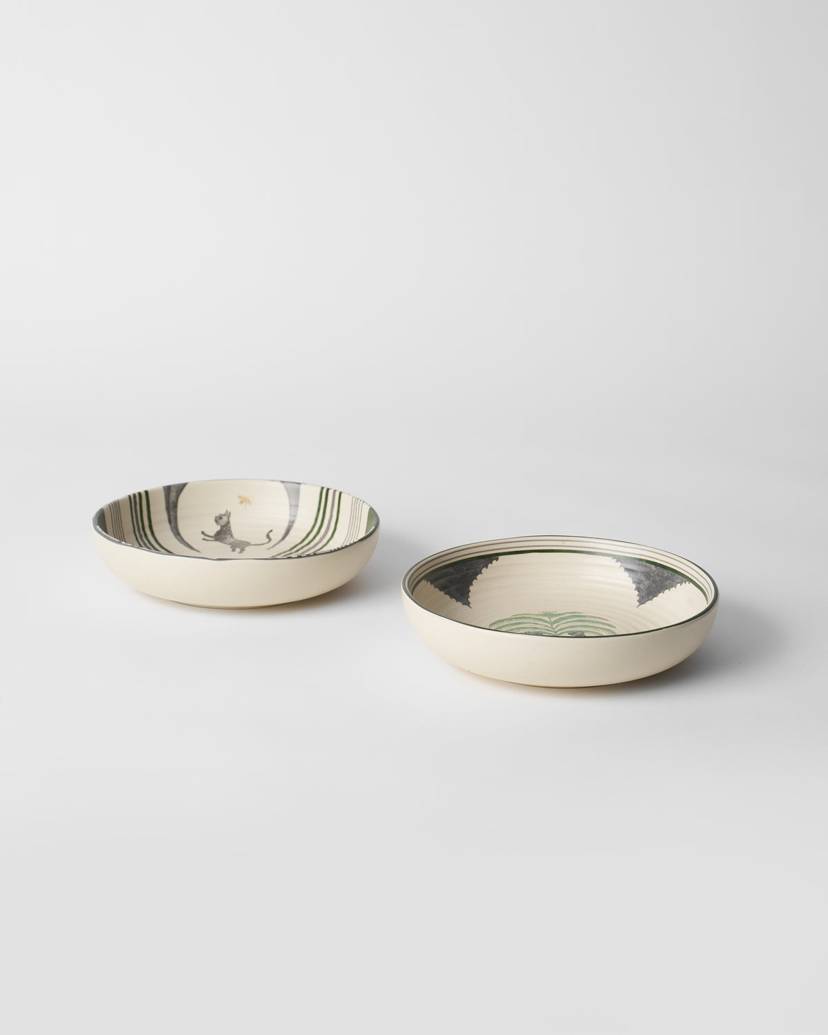 Indus Shallow Bowls with leopard and palm motifs on cream interiors.