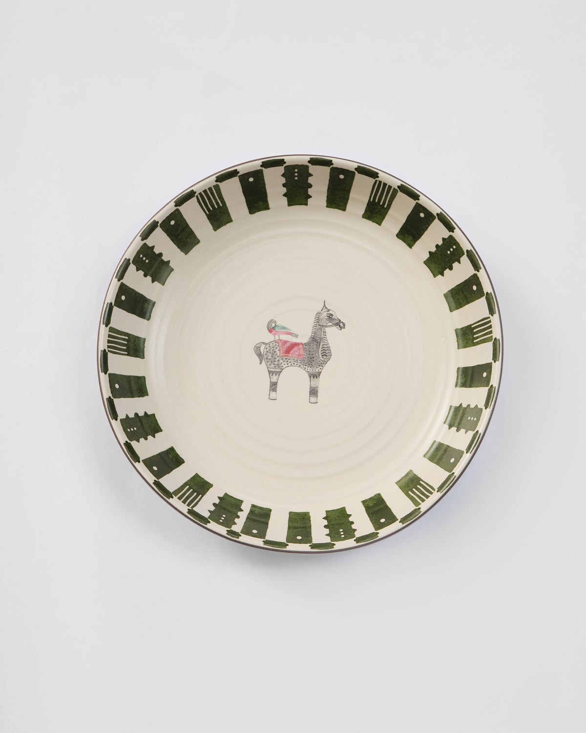 Overhead view of an Indus pasta plate with horse motif and green rim.