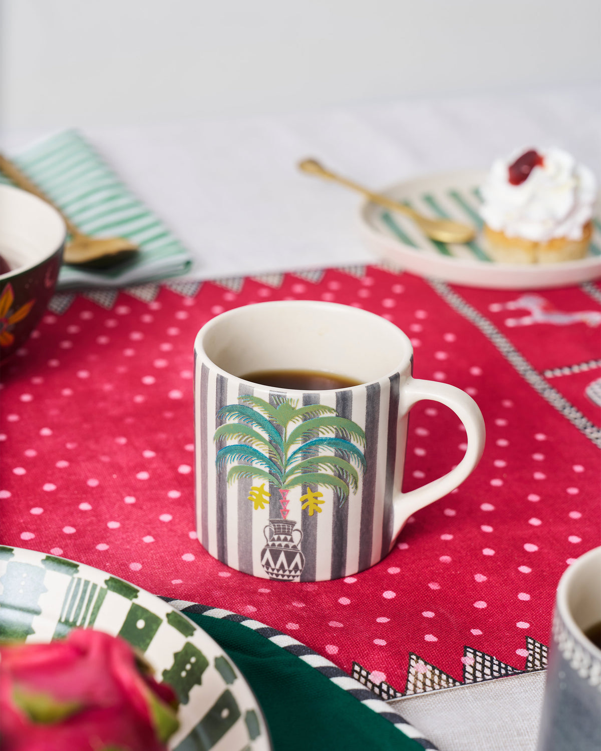 Indus Straight Mug filled with tea, showing its palm tree motif.