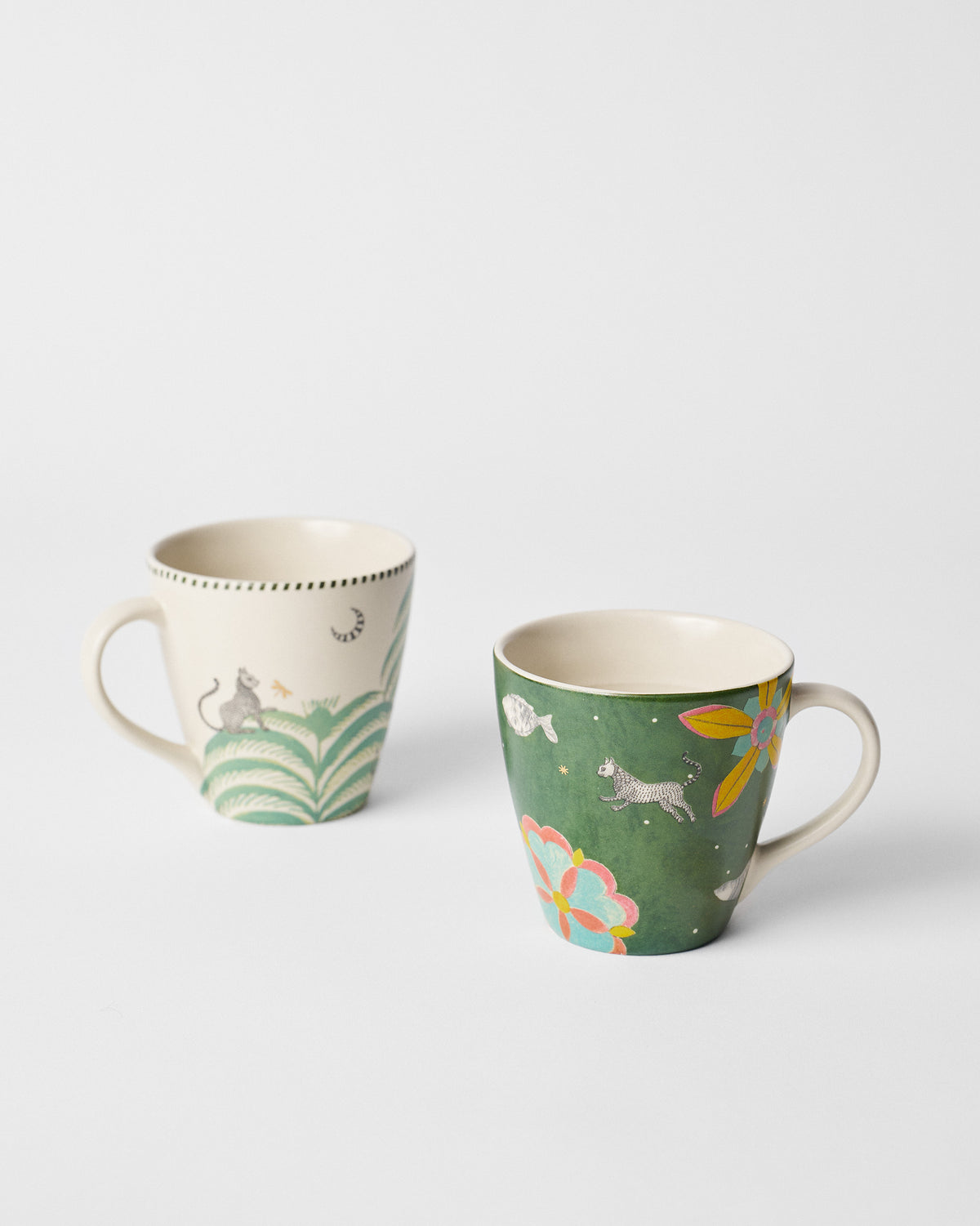 Pair of conical Indus mugs in cream and green with jungle animal prints.