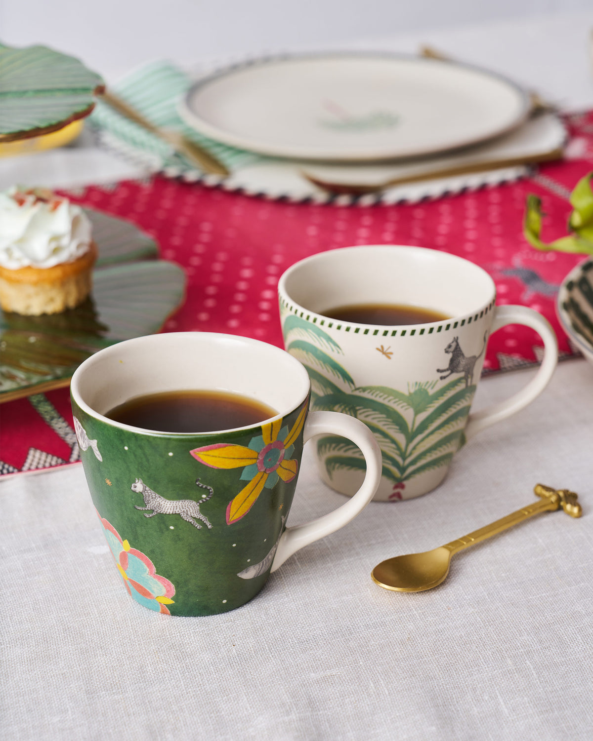Cream and forest-green Indus mugs filled with a dark drink on a table.