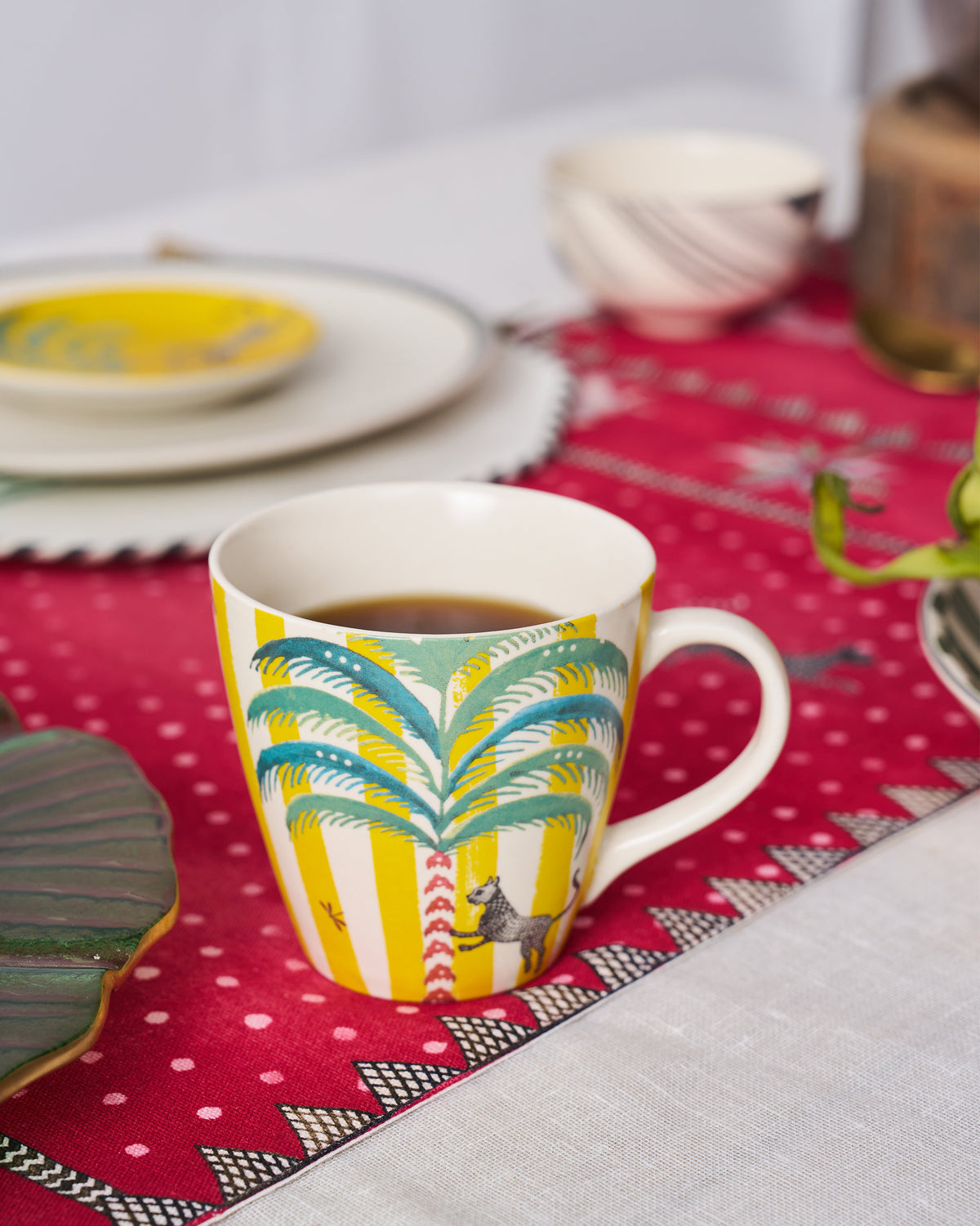 The Bagh Conical Mug with tea on a pink tablecloth.