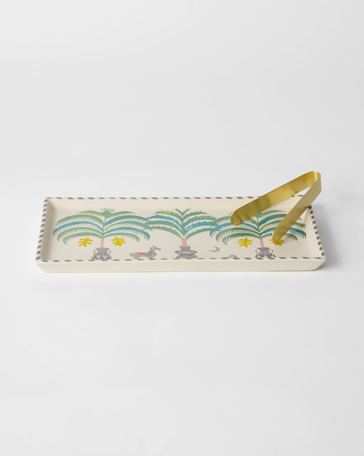 Indus cookie tray with potted palm motifs and gold tongs resting on top.