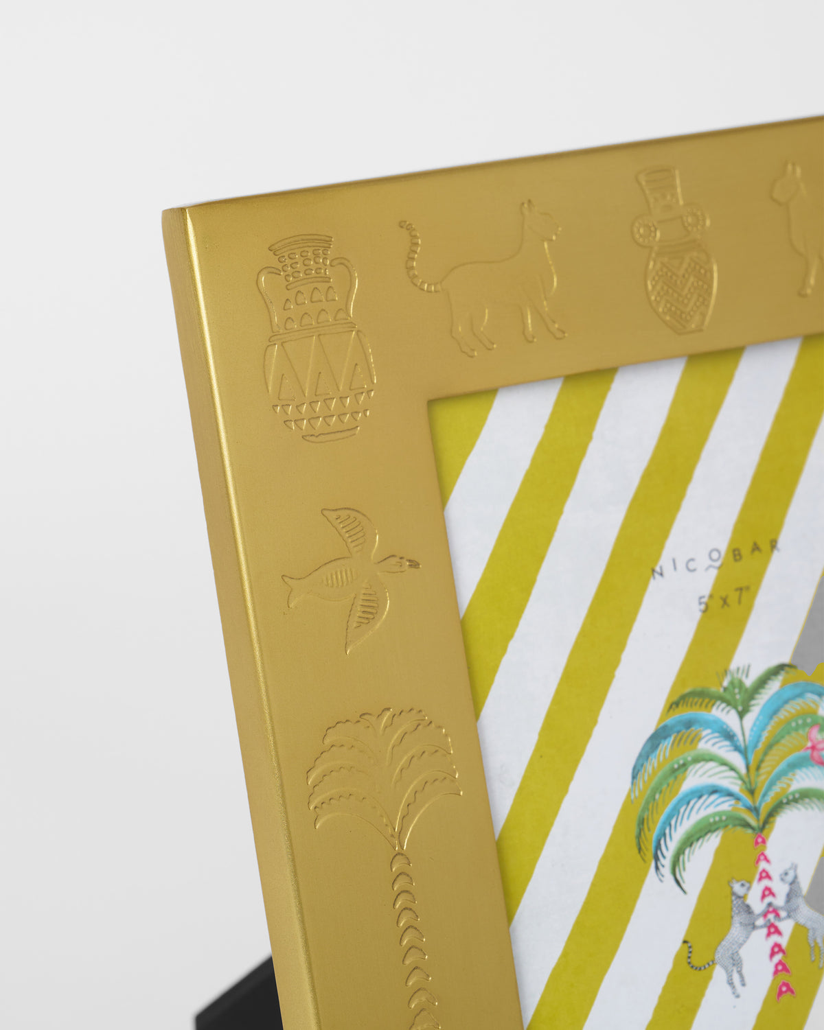 Close-up of embossed urns, palms, and animals on an Indus photo frame.