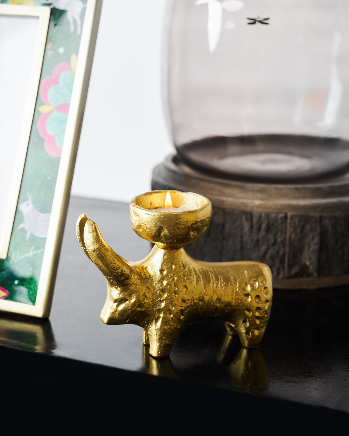 Bull Tealight Holder in gold with a lit tealight in its cup.