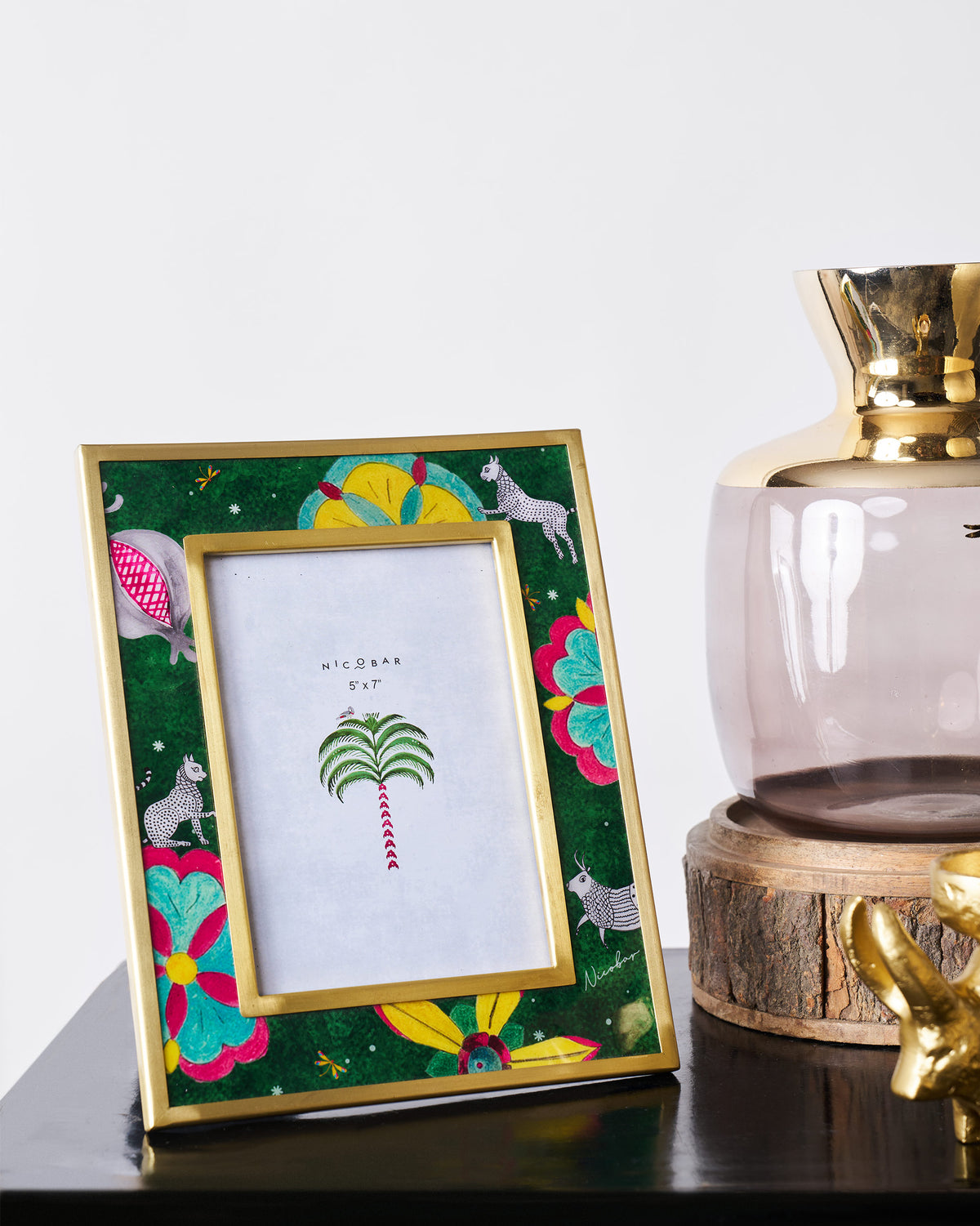Gold Anara photo frame with flowers and animals on a black surface.