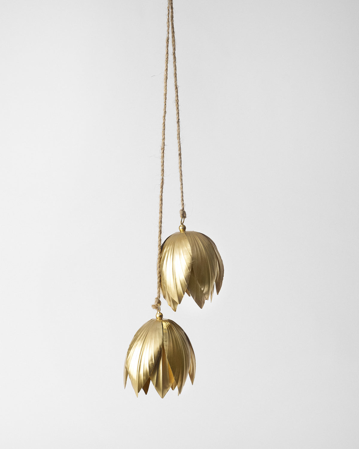 Pair of gold lotus-petal bells hanging from natural jute cord.