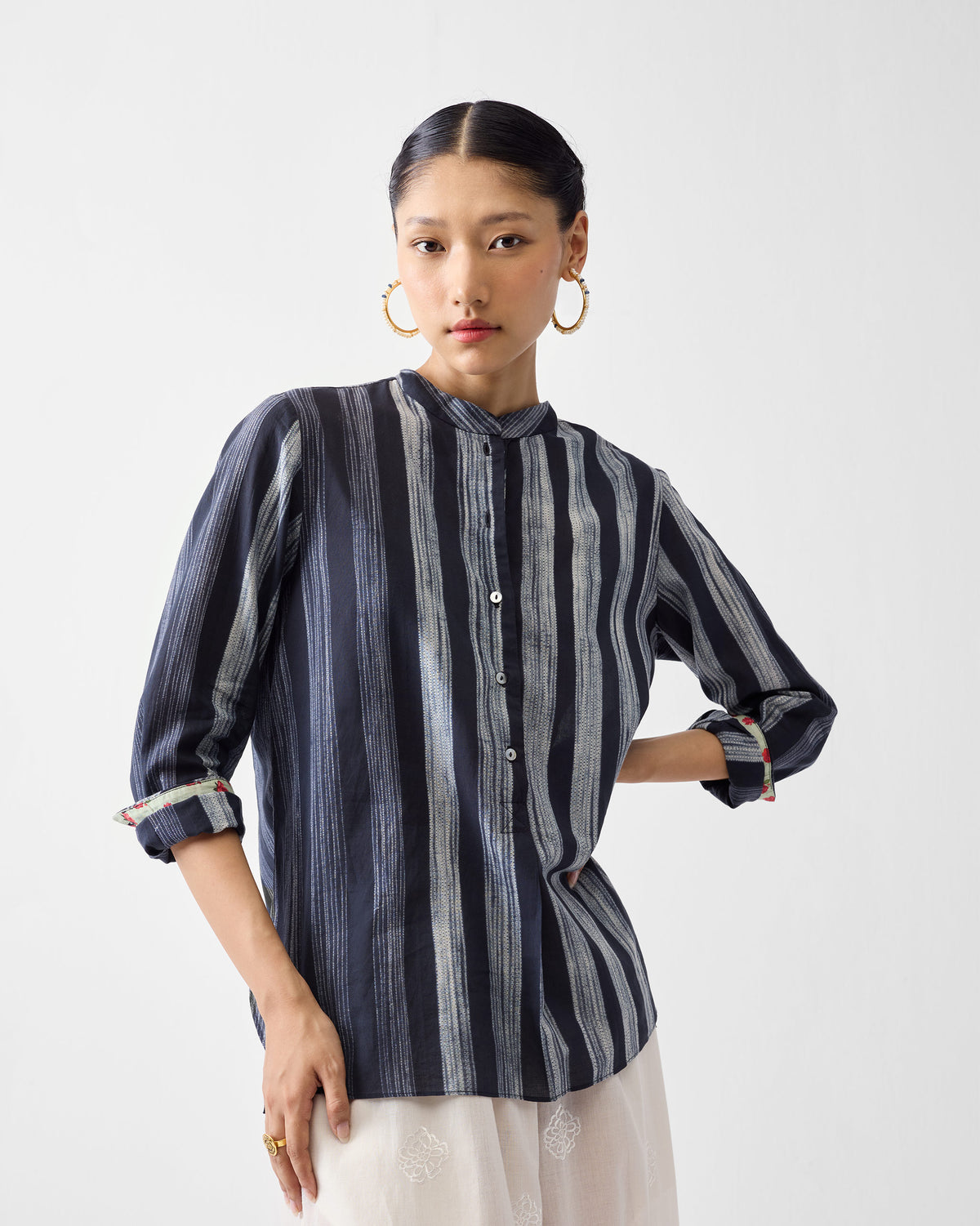 Person wearing a charcoal and ivory striped mandarin collar top.
