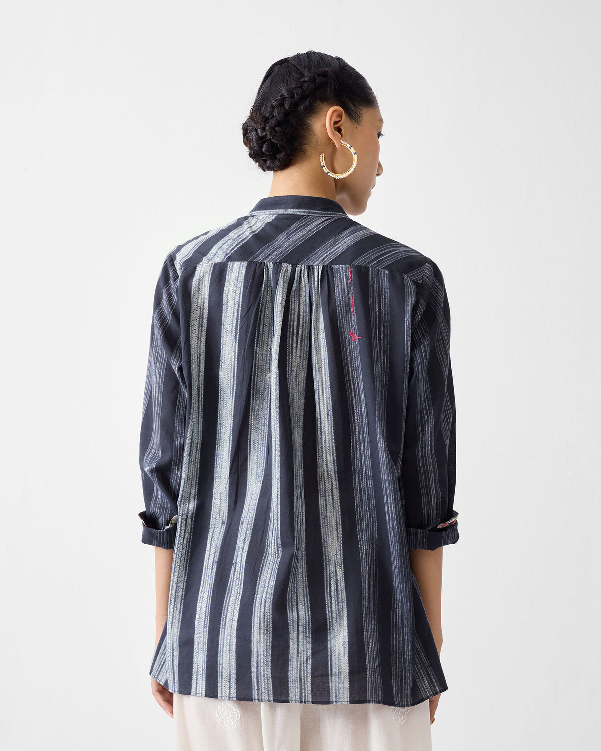 Back of a charcoal and ivory striped mandarin collar top with a gathered yoke.