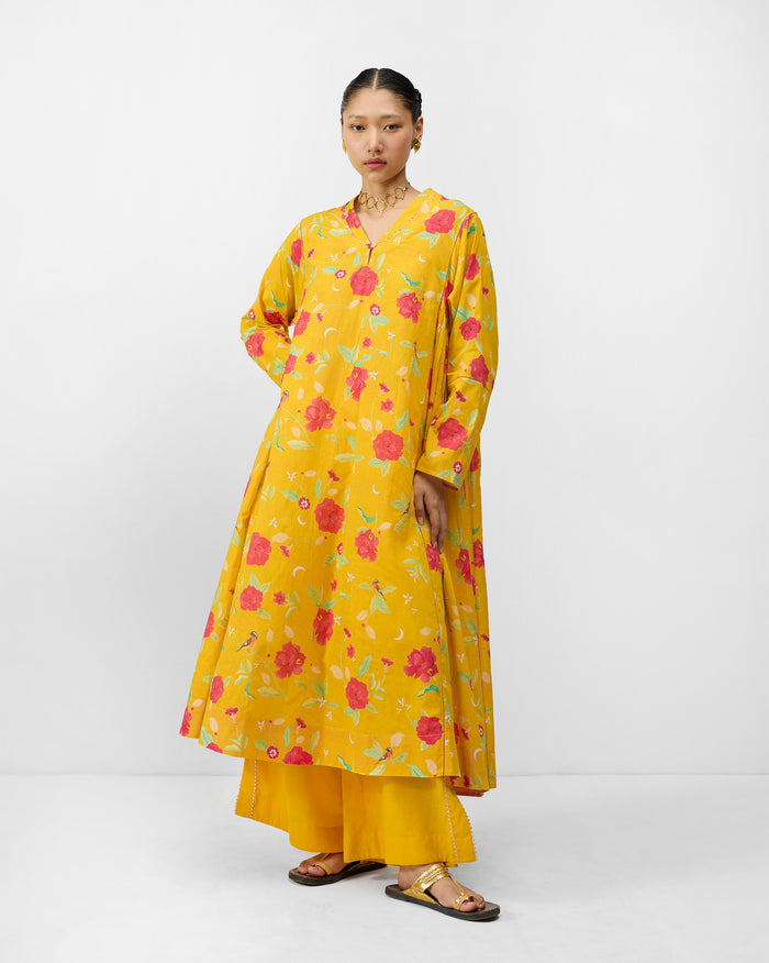 Person wearing a turmeric yellow Amreli kurta with watermelon peony print.
