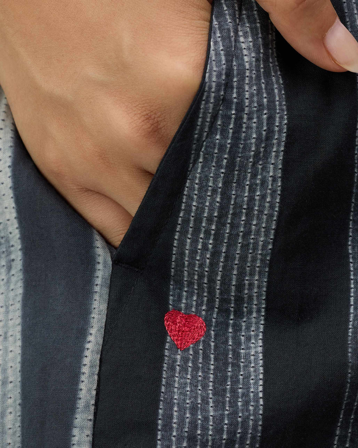Close-up of Areca Pants showing a red heart embroidered below the pocket.