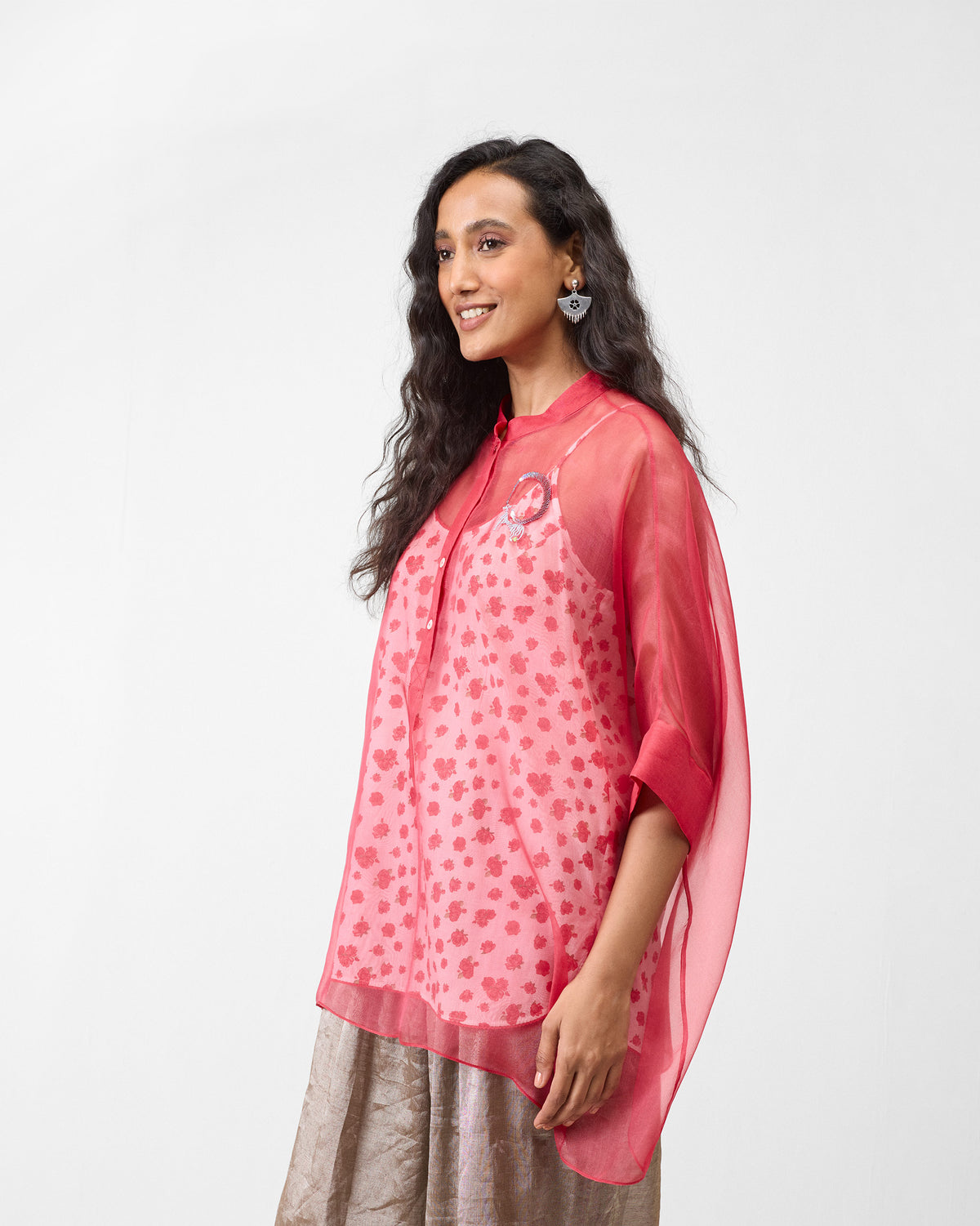 Person wearing a sheer watermelon shirt with wide sleeves.