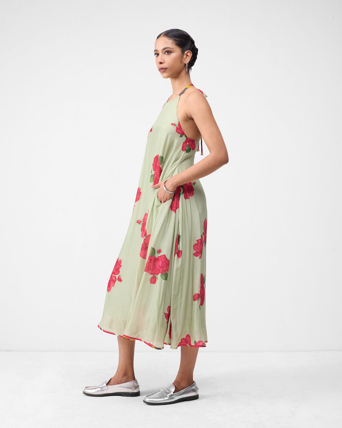 Side view of a mint watermelon print scoop back dress with a midi hem and pocket.