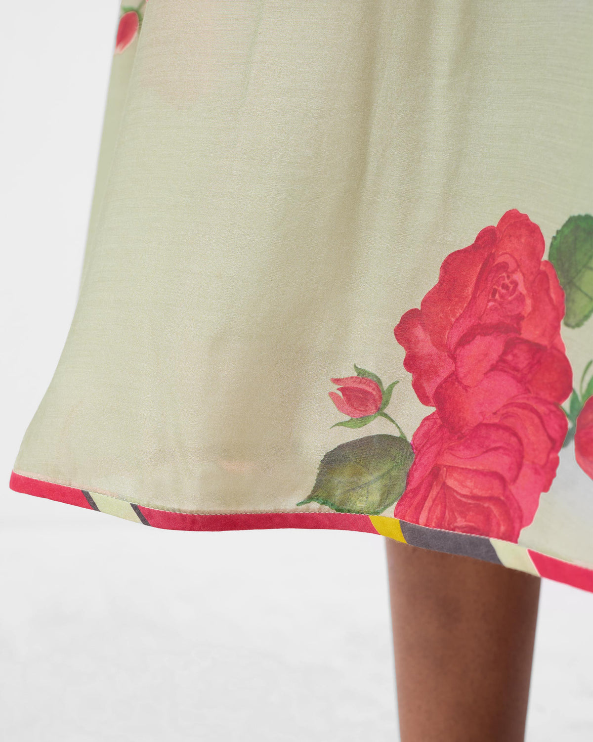Close-up of the scoop back dress hem with a red rose print and pink piping.