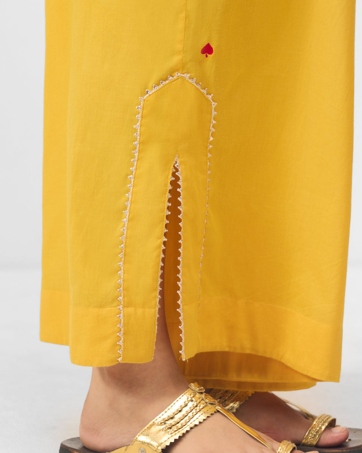 Close-up of turmeric yellow Ayat pyjamas showing the embroidered side-slit hem.