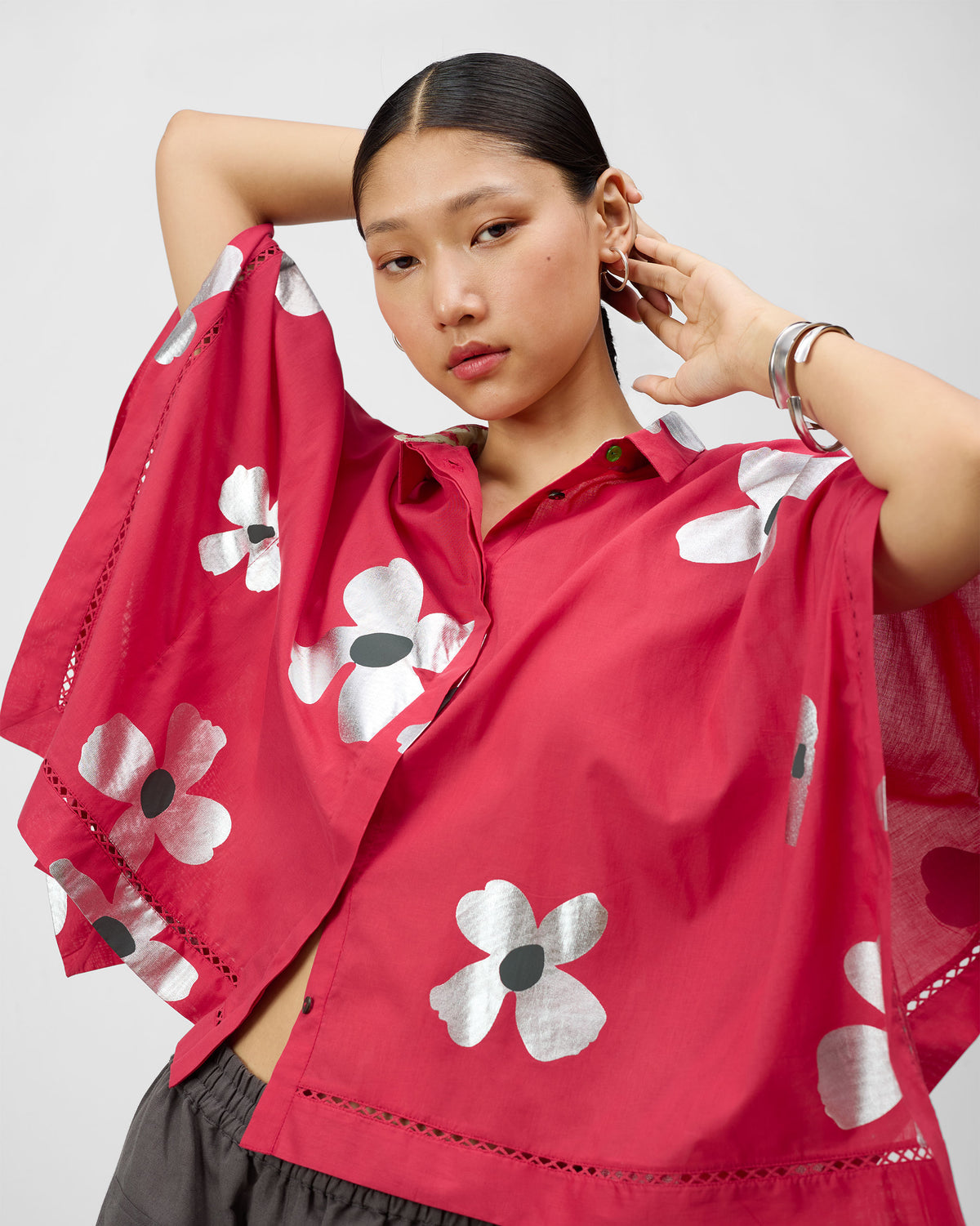 Person wearing an oversized watermelon pink top with silver foil flowers.