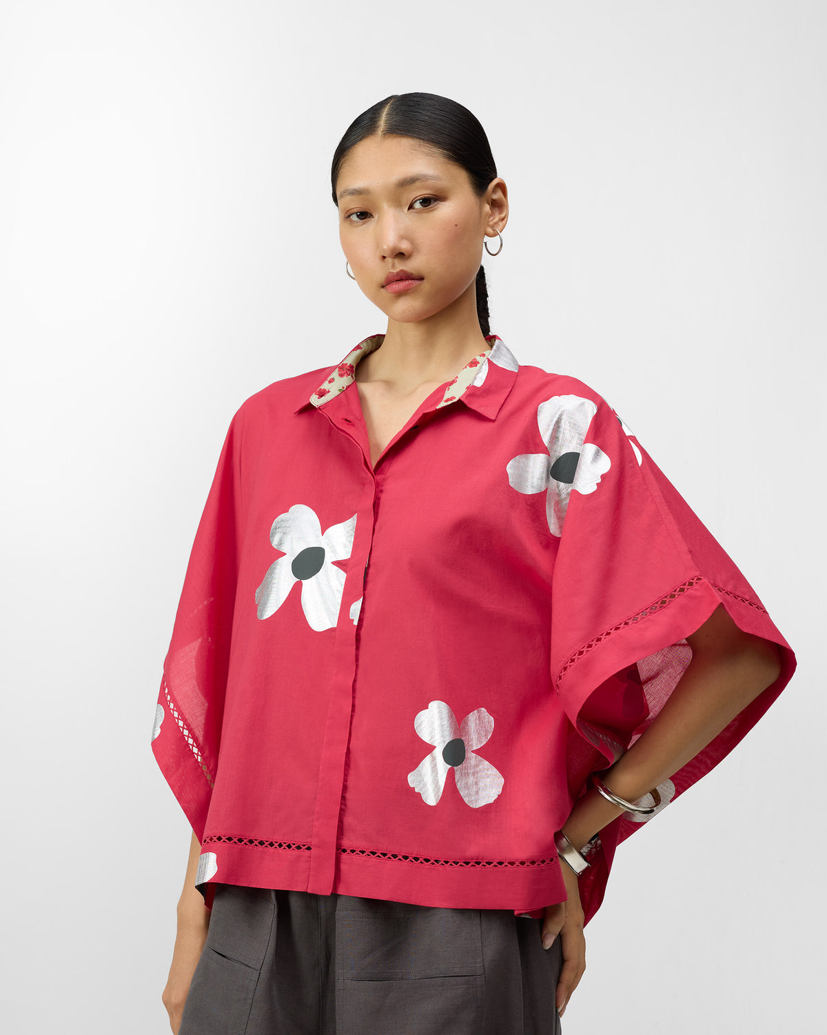 Person wearing a watermelon pink floral top with a rose-print collar lining.