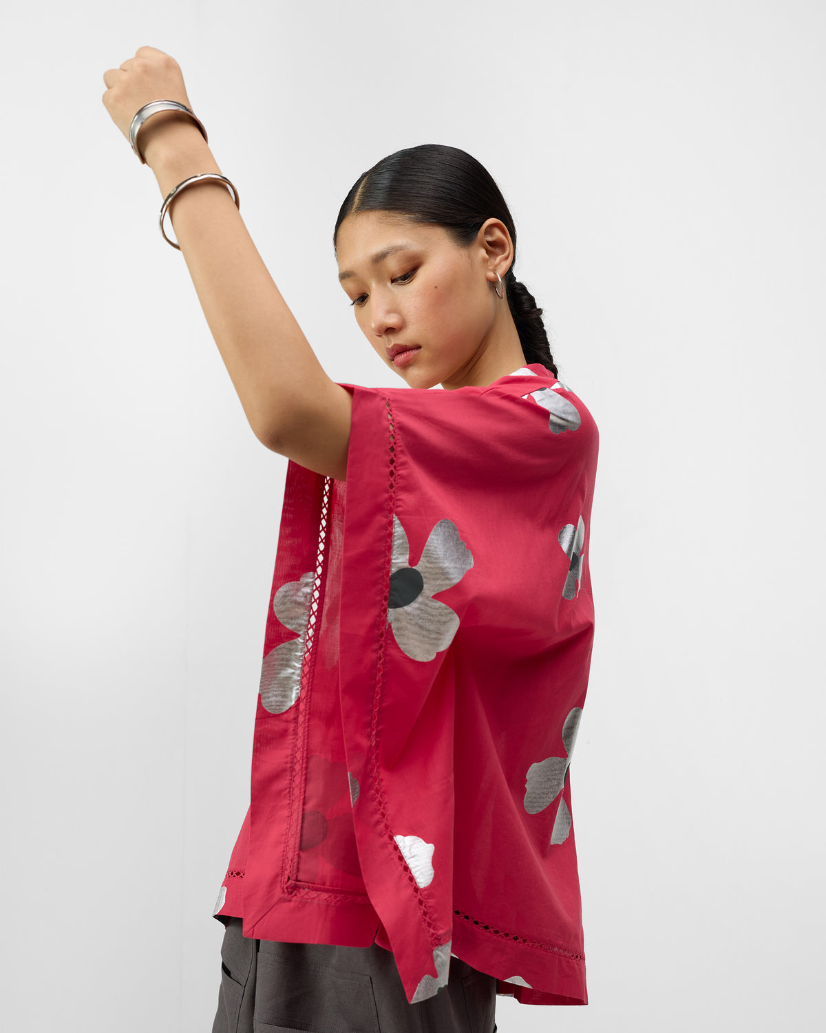 Side view of a watermelon pink top with ladder lace and silver flowers.