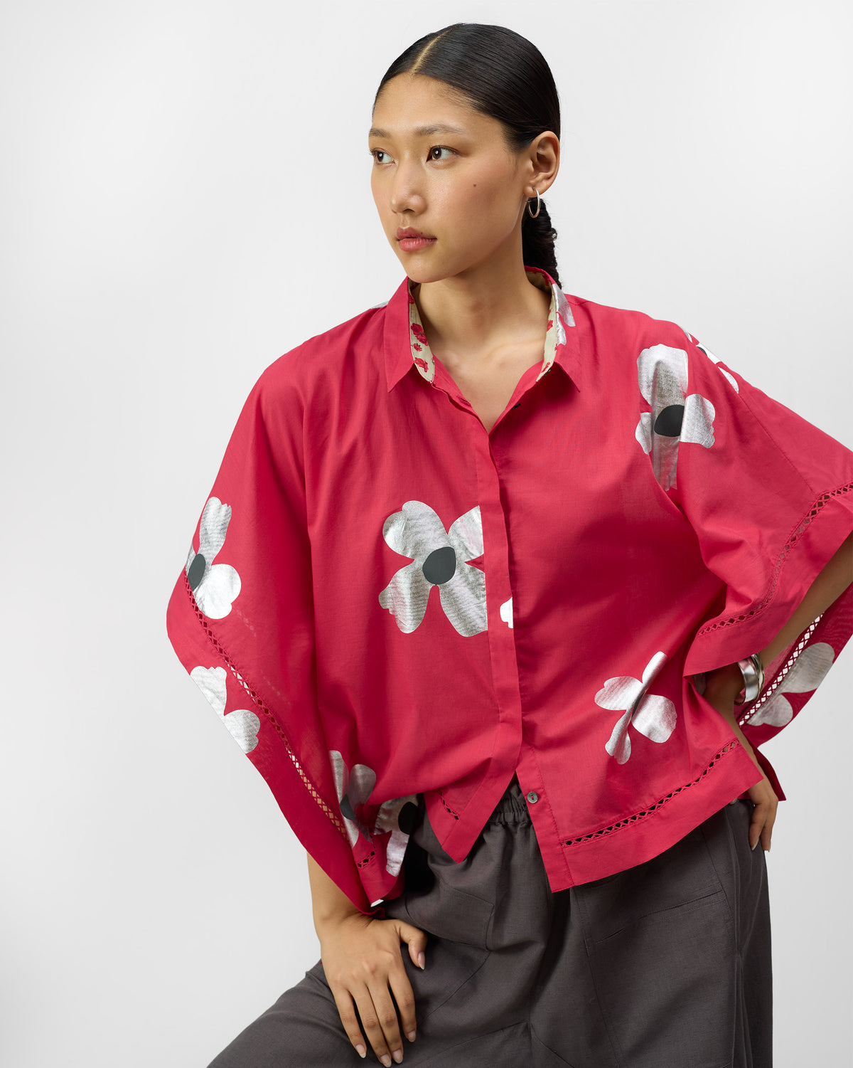 Person wearing a watermelon pink top with silver foil flowers and lace trim.