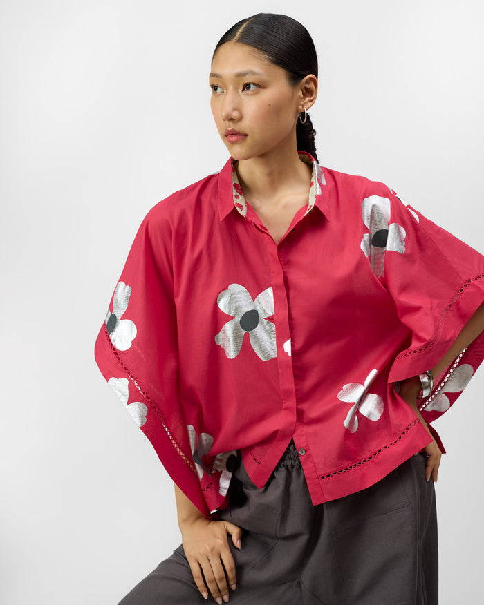 Person wearing a watermelon pink top with silver foil flowers and lace trim.
