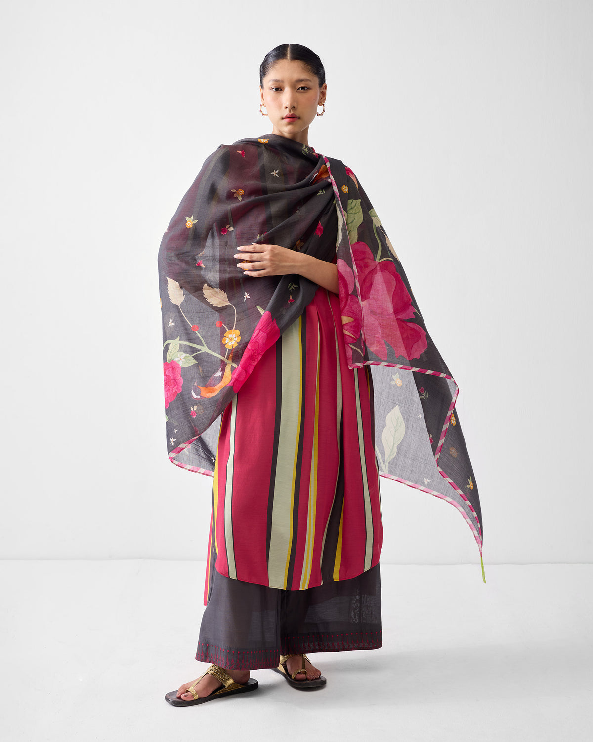 Person wearing a multicolor striped kurta under a floral scarf.
