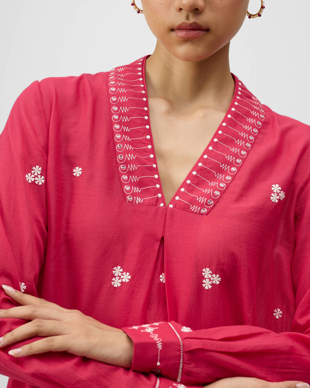 Close-up of ivory embroidery on a watermelon pink Banko kurta neckline.