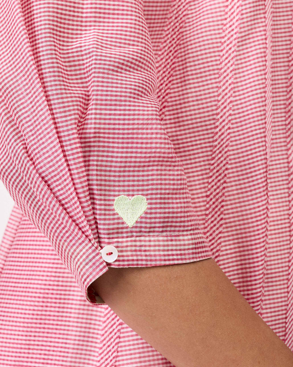Close-up of a pink gingham cuff with a green heart on a Pattaya kurta.