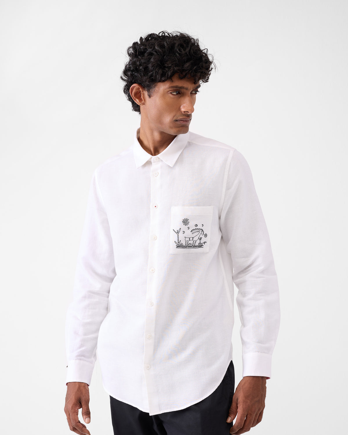 Person wearing a white Musafir Pocket Shirt with goat pocket embroidery.