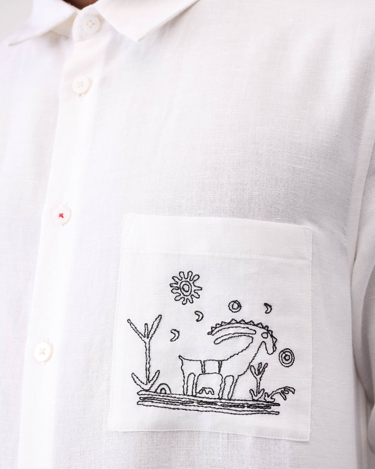 Close-up of goat embroidery on the pocket of a white Musafir Pocket Shirt.