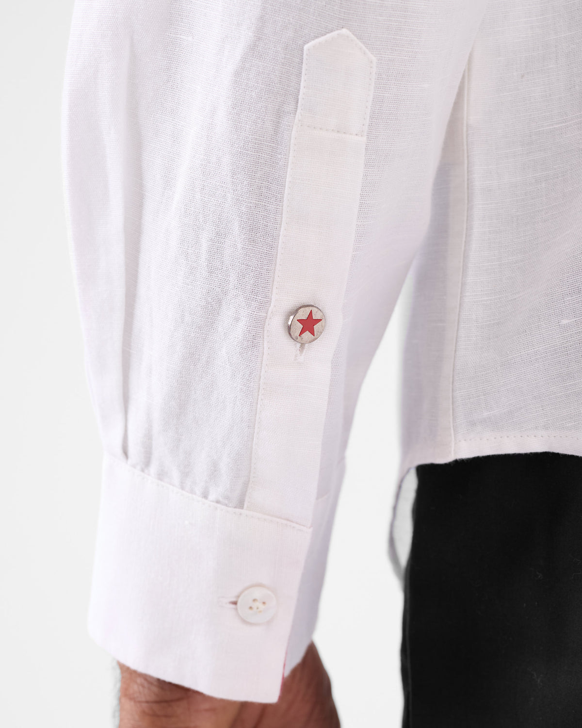 Close-up of a white Musafir Pocket Shirt cuff with a red star button.