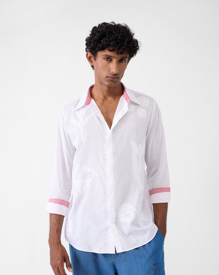 Person wearing a white Hakuna Shirt with tonal appliqués and gingham cuffs.