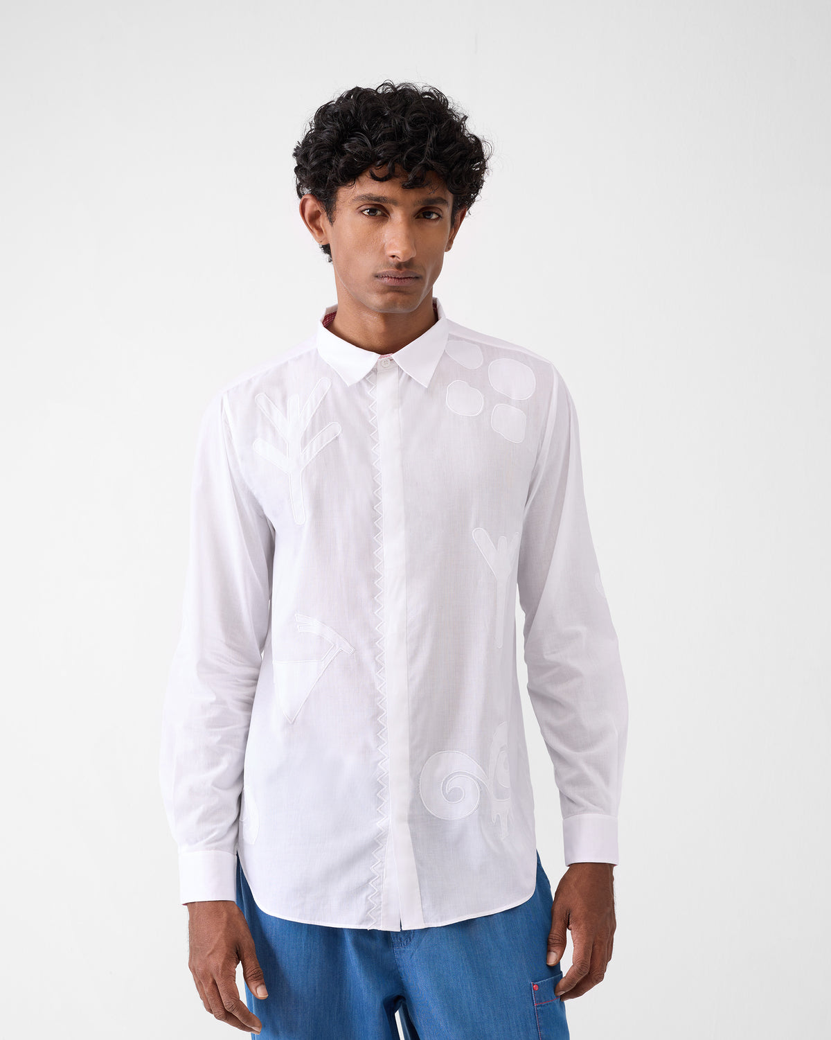 Person wearing a white Hakuna Shirt with tonal appliqués and a concealed placket.