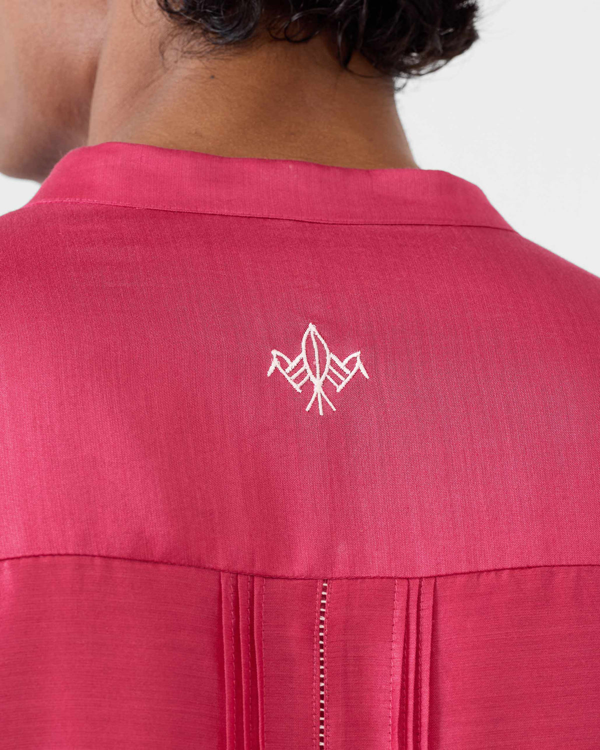 Close-up of white bird embroidery on the back of a watermelon Naaz kurta.