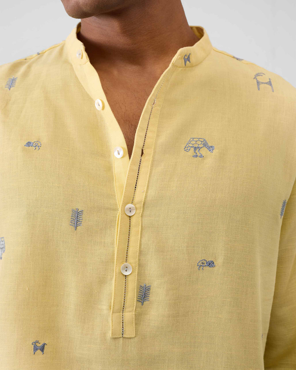 Close-up of a light yellow Astral kurta showing grey embroidered animal icons.